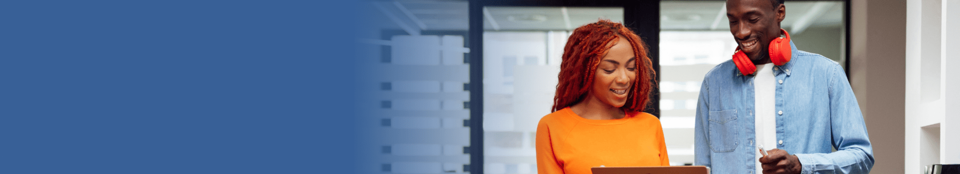Office setting with two people standing near a laptop beside a blue banner displaying the word ‘Blogs’, representing workplace insights and blog content.